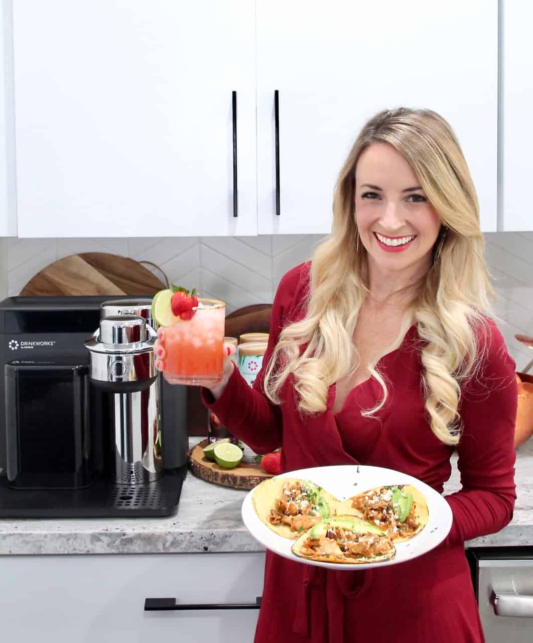 woman holding plate of tacos and strawberry margarita