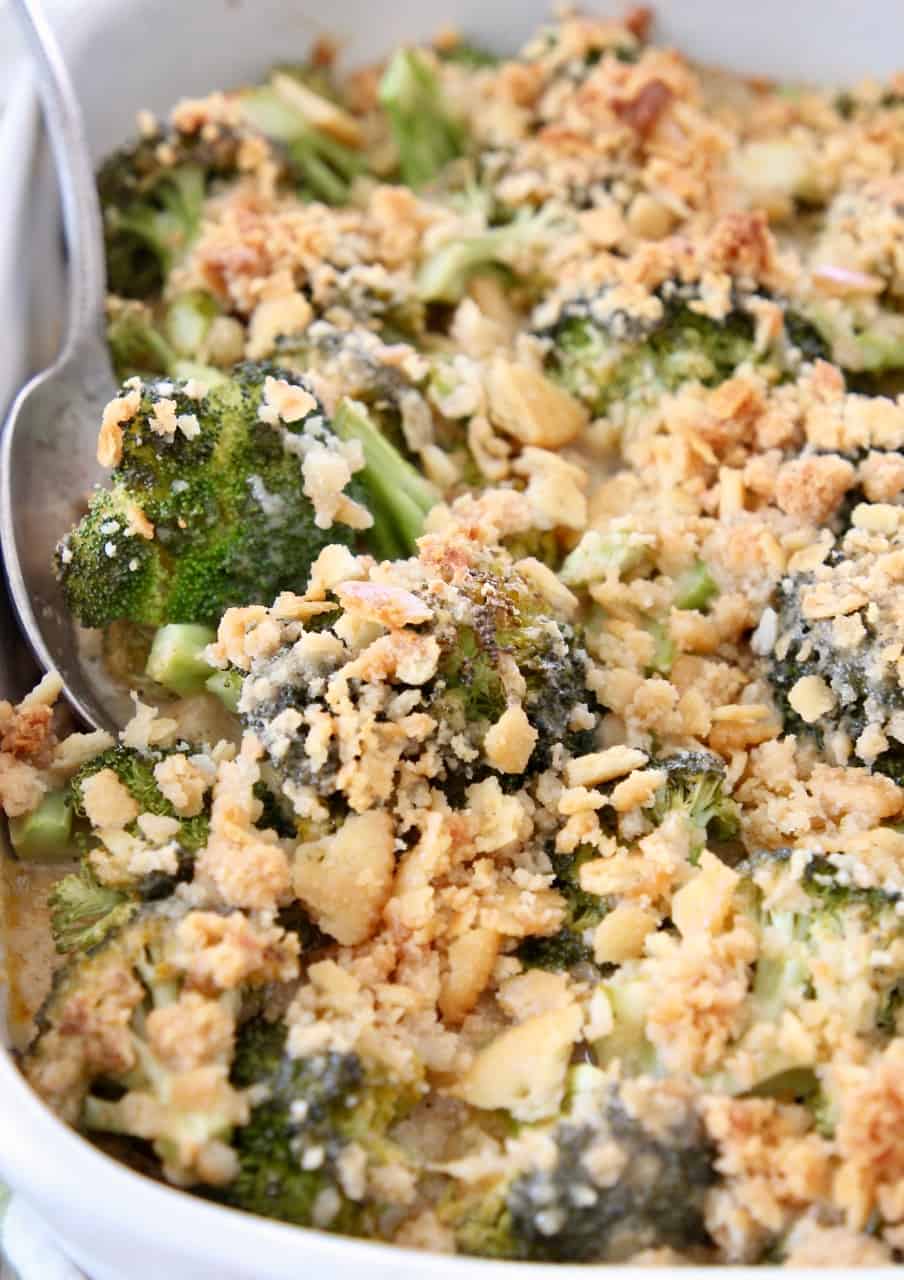 broccoli casserole topped with ritz crackers with serving spoon in the dish