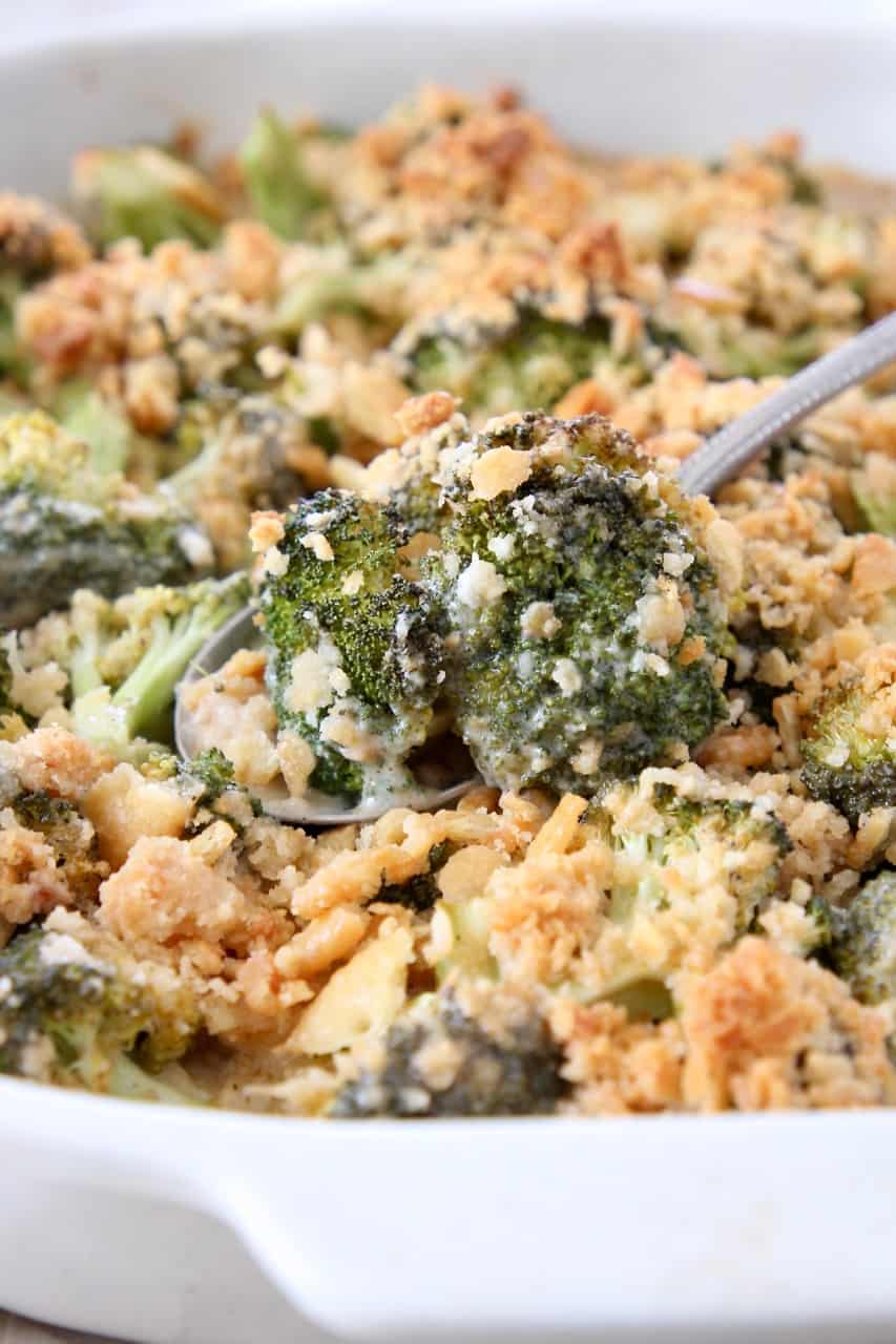 broccoli cheese casserole with serving spoon lifting broccoli out of the dish