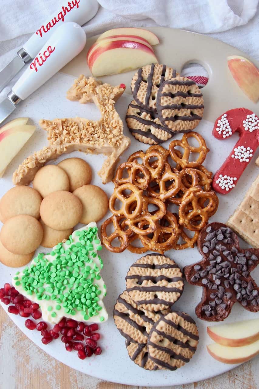 overhead image of dessert board with pretzels, cookies and cream cheese dip in holiday shapes