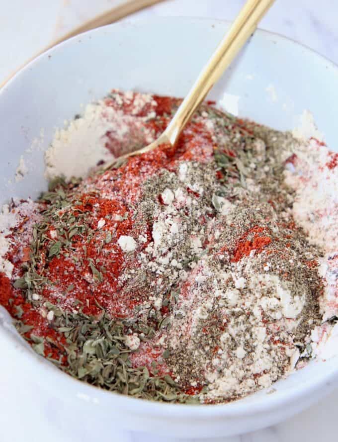 mixed spices and herbs in bowl with gold spoon