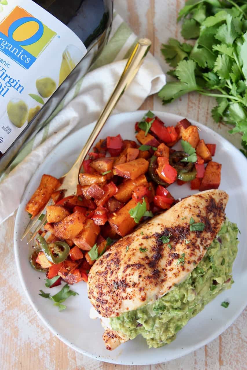 overhead image of guacamole stuffed chicken on plate with roasted vegetables