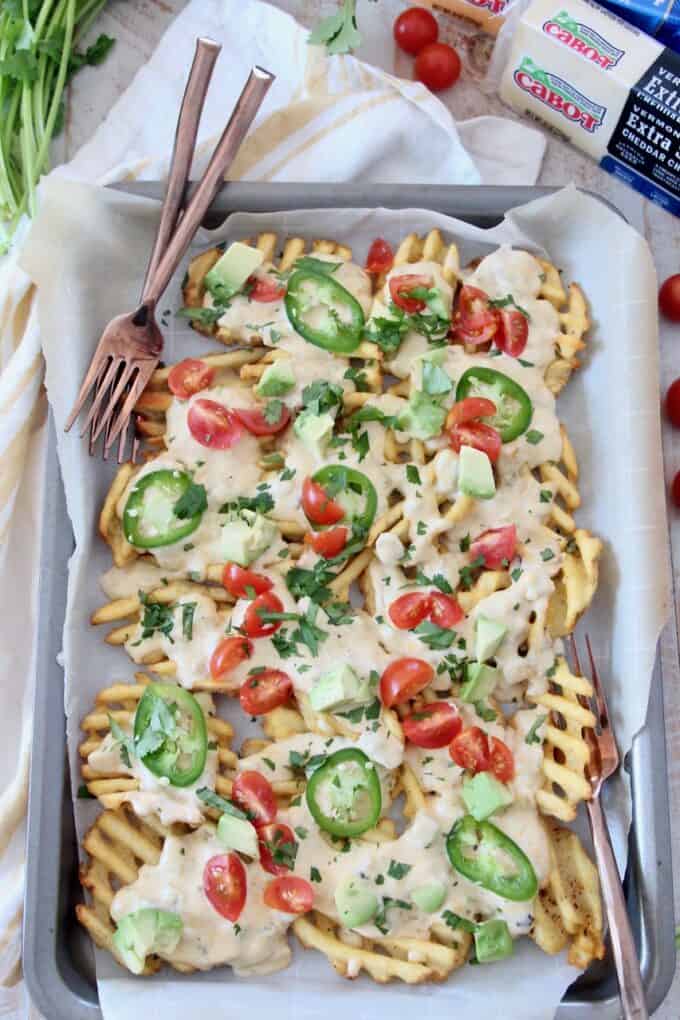 overhead image of waffle fry nachos on sheet pan with forks