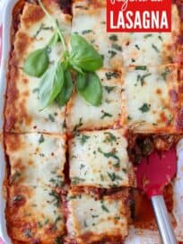 overhead image of lasagna in casserole dish cut into squares with red spatula