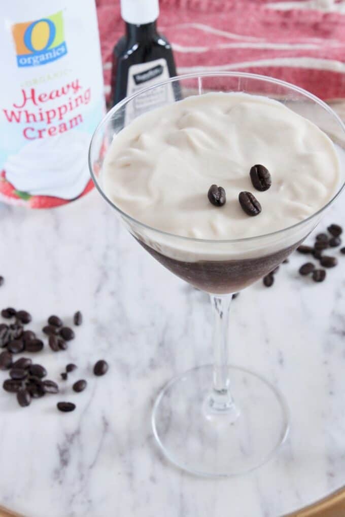 espresso martini topped with whipped cream in martini glass