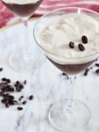 two espresso martinis on marble serving tray with coffee beans
