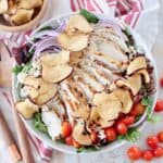 sliced chicken on top of salad in bowl with apple chips