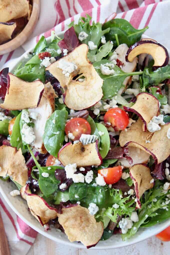 salad in bowl tossed with apple chips and gorgonzola cheese