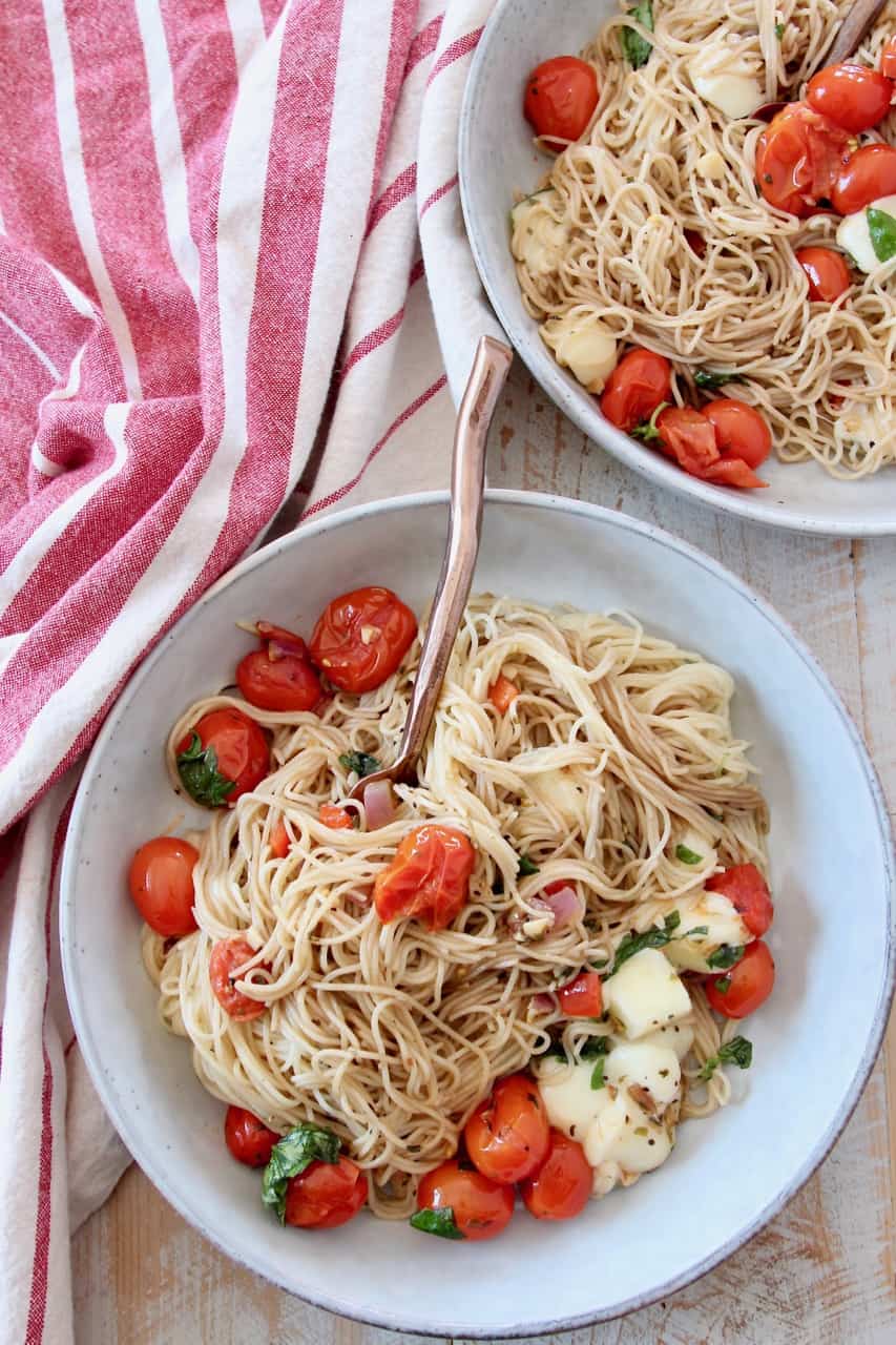 angel hair pasta in bowls with cherry tomatoes and mozzarella cubes