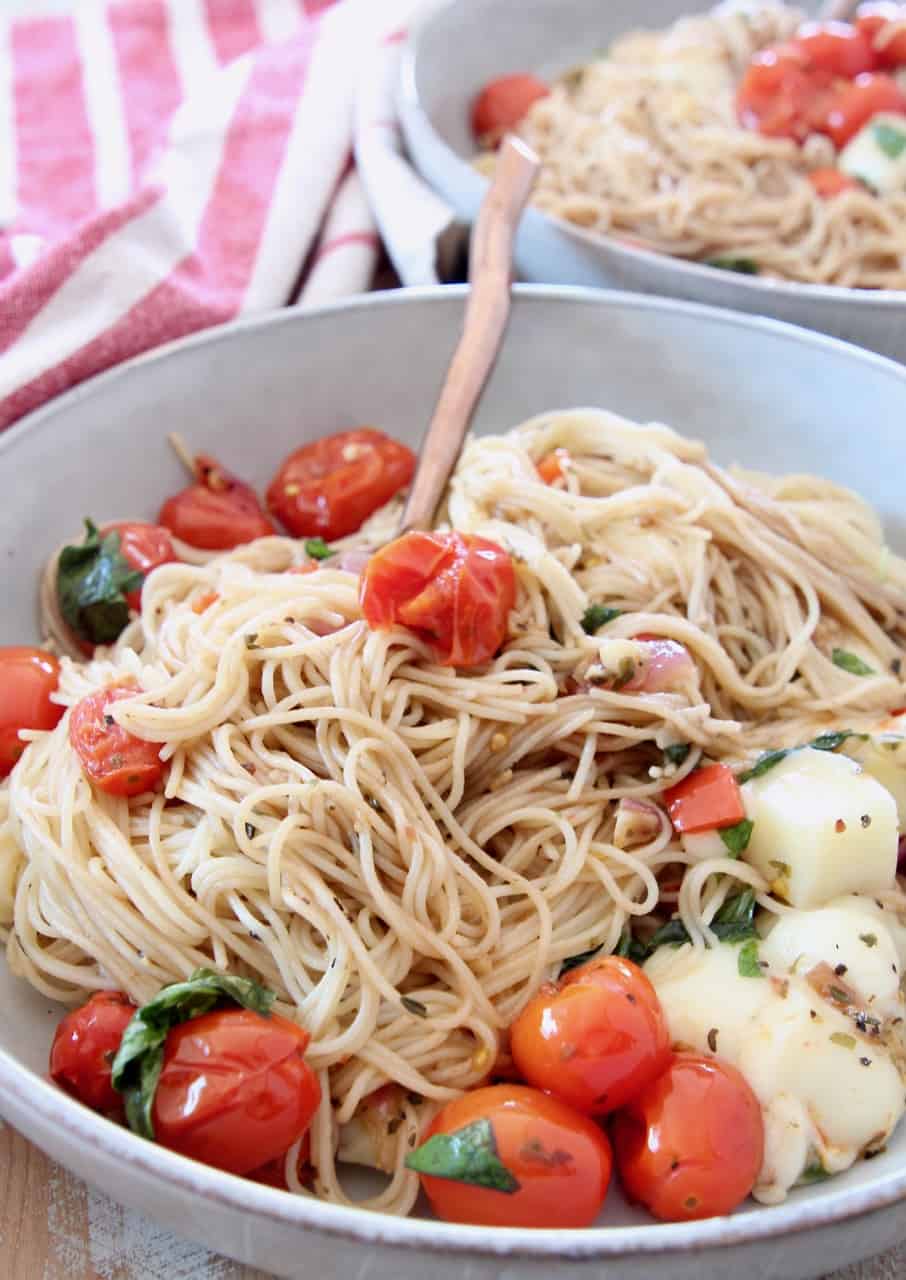 caprese pasta with angel hair pasta in bowl with fork