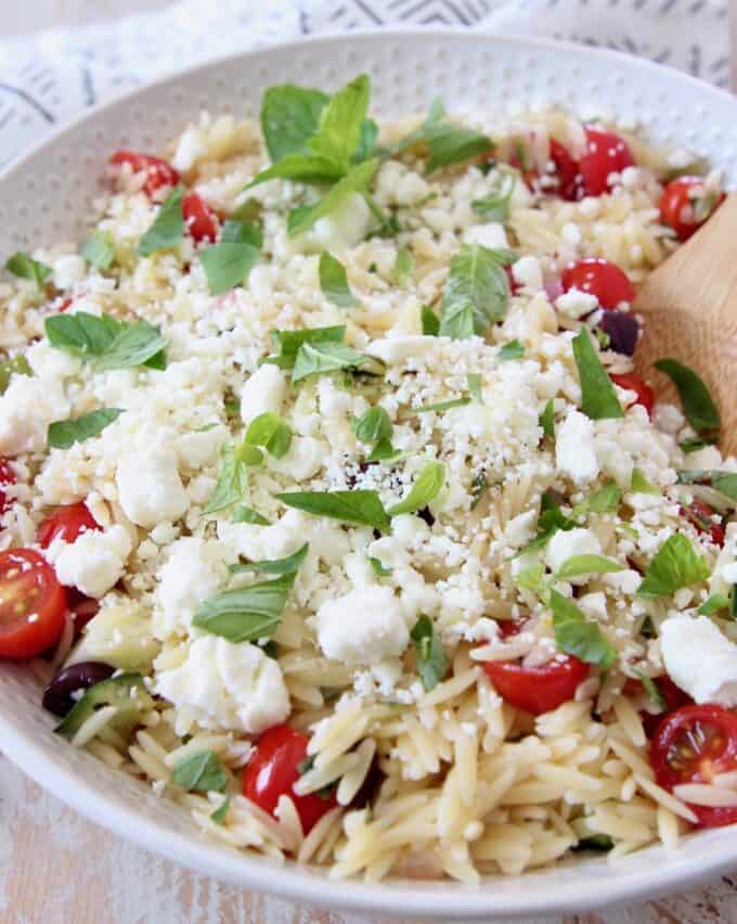 orzo pasta salad in bowl topped with fresh mint and feta cheese