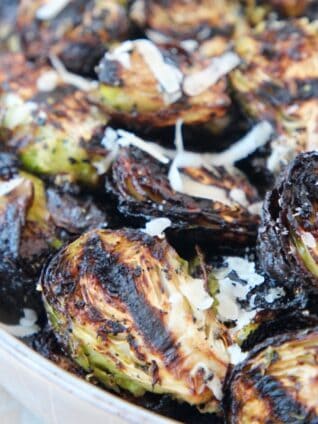 grilled brussels sprouts in bowl topped with grated parmesan cheese
