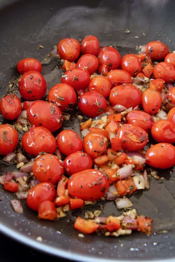 cooked cherry tomatoes with diced onions and peppers in a large skillet