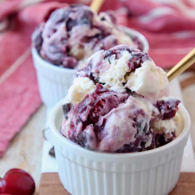 scoops of cherry ice cream in bowl with gold spoon