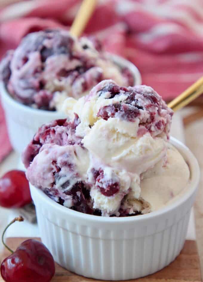 scoops of cherry ice cream in white bowl with gold spoon