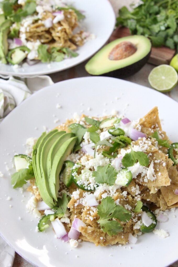 chilaquiles verdes on plate topped with cilantro and cotija cheese