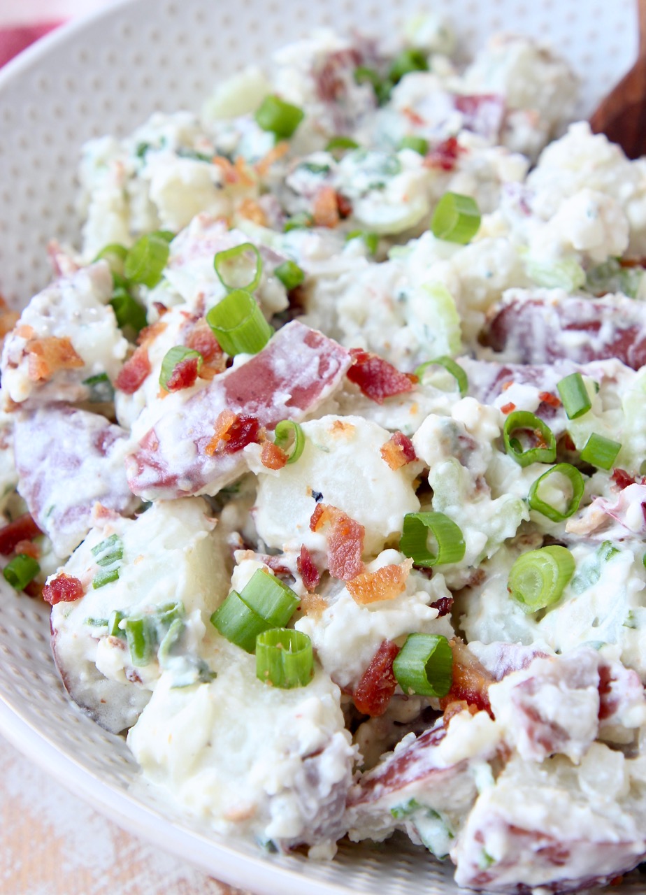 potato salad in white bowl topped with diced green onions
