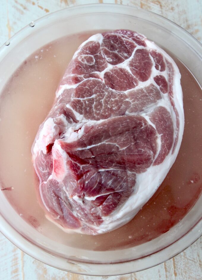 pork shoulder in brine in a large glass bowl