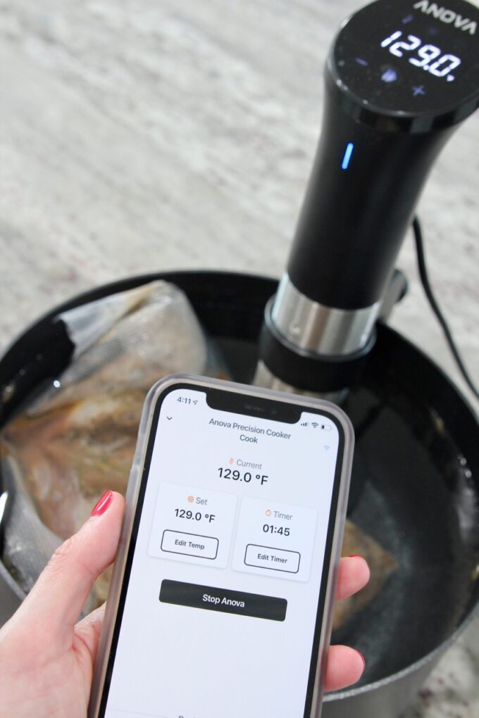 phone displaying app for sous vide in front of sous vide attached to pot