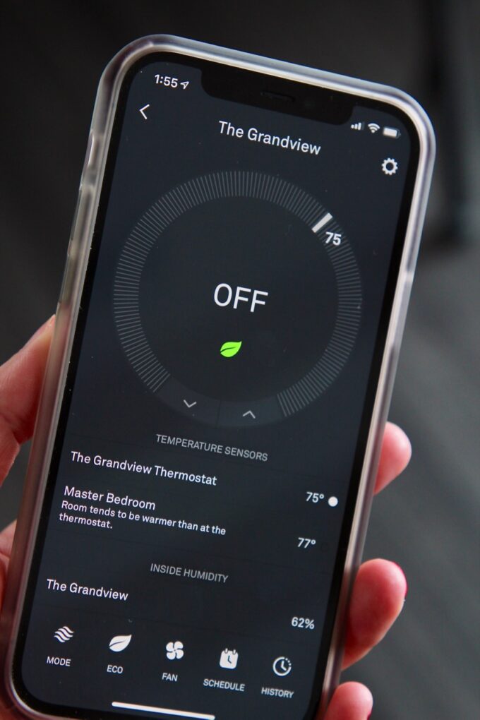 hand holding iphone with nest app showing on the phone