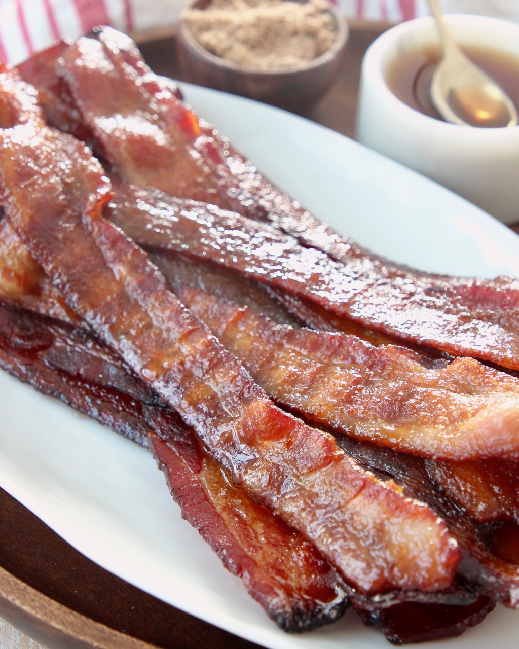 cooked candied bacon piled up on white plate