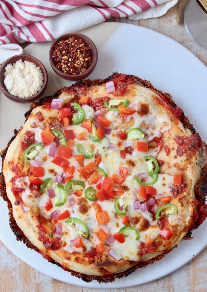 cooked pan pizza topped with veggies on marble serving tray