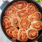 cooked pizza rolls in black baking dish