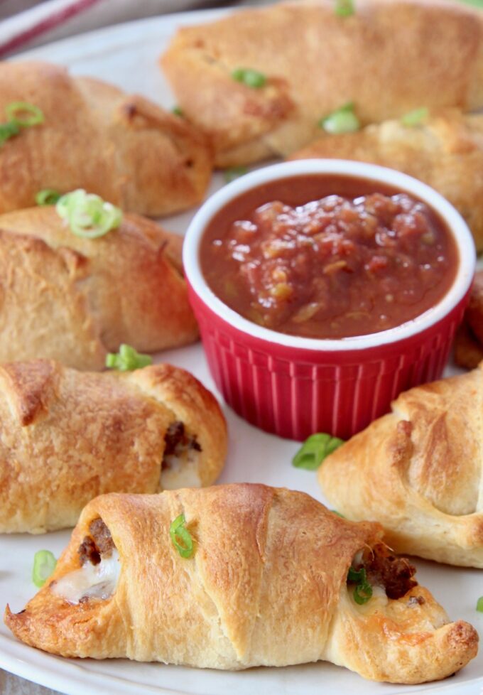cooked taco filled crescent rolls on plate with bowl of salsa