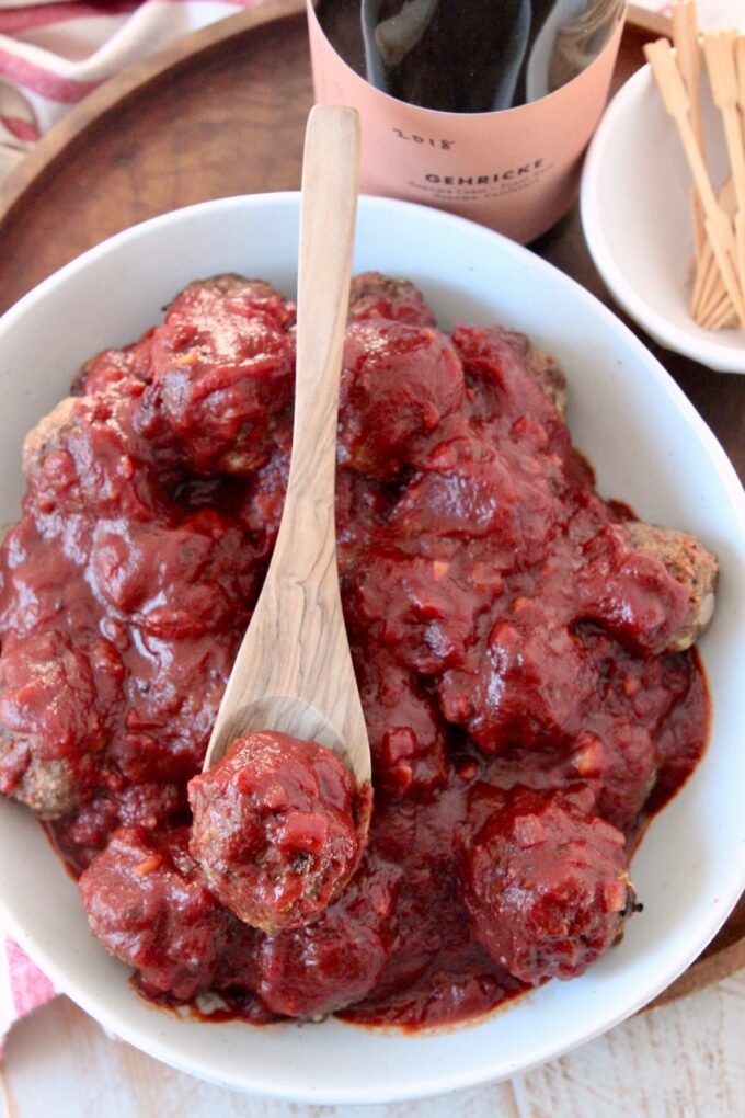 bbq sauce covered meatballs in bowl with wooden spoon
