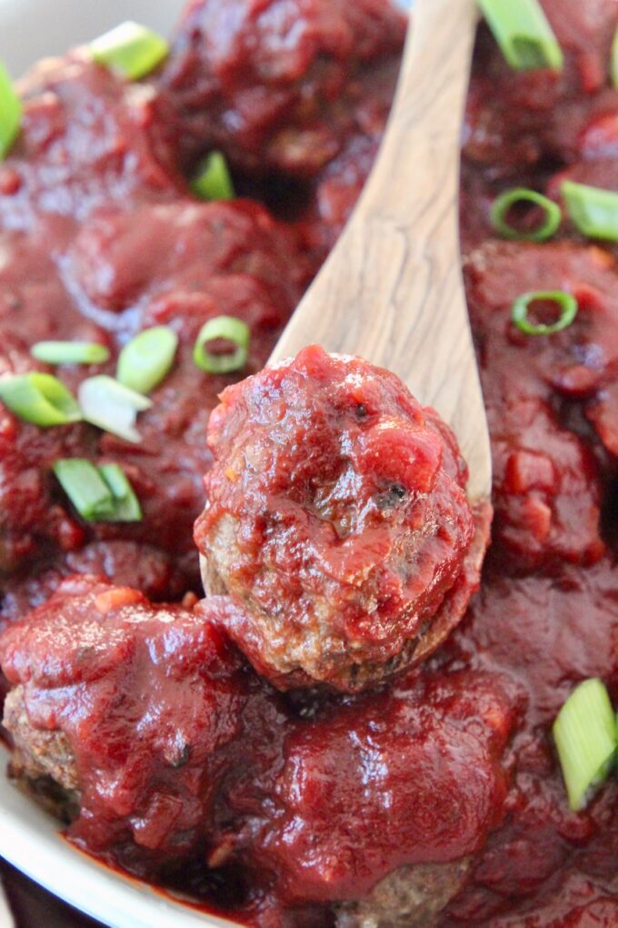 meatballs with bbq sauce in bowl and meatball on a spoon in the bowl