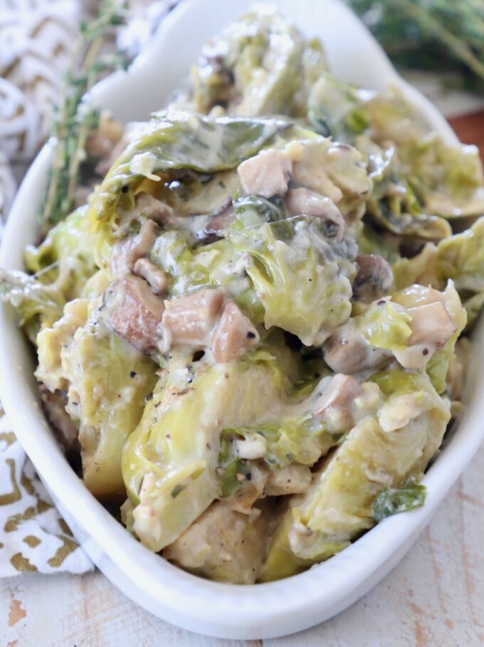 cooked brussels sprouts in serving bowl with creamy mushroom sauce