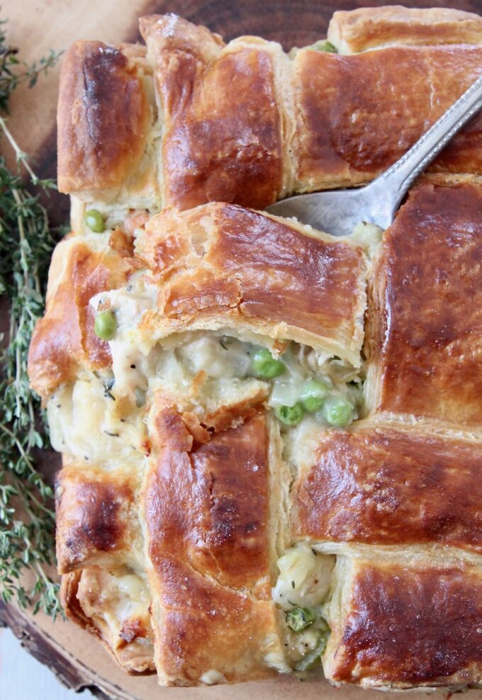 spoon dipping into baked chicken pot pie with puff pastry crust