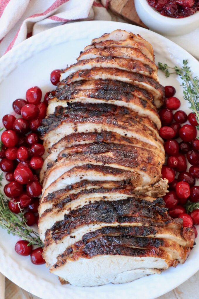 sliced turkey breast on plate with fresh cranberries on the side