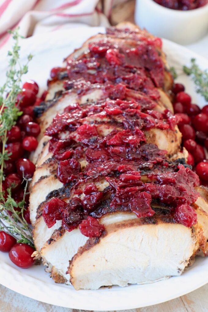 slices of turkey breast on plate with cranberry sauce on top of the turkey slices