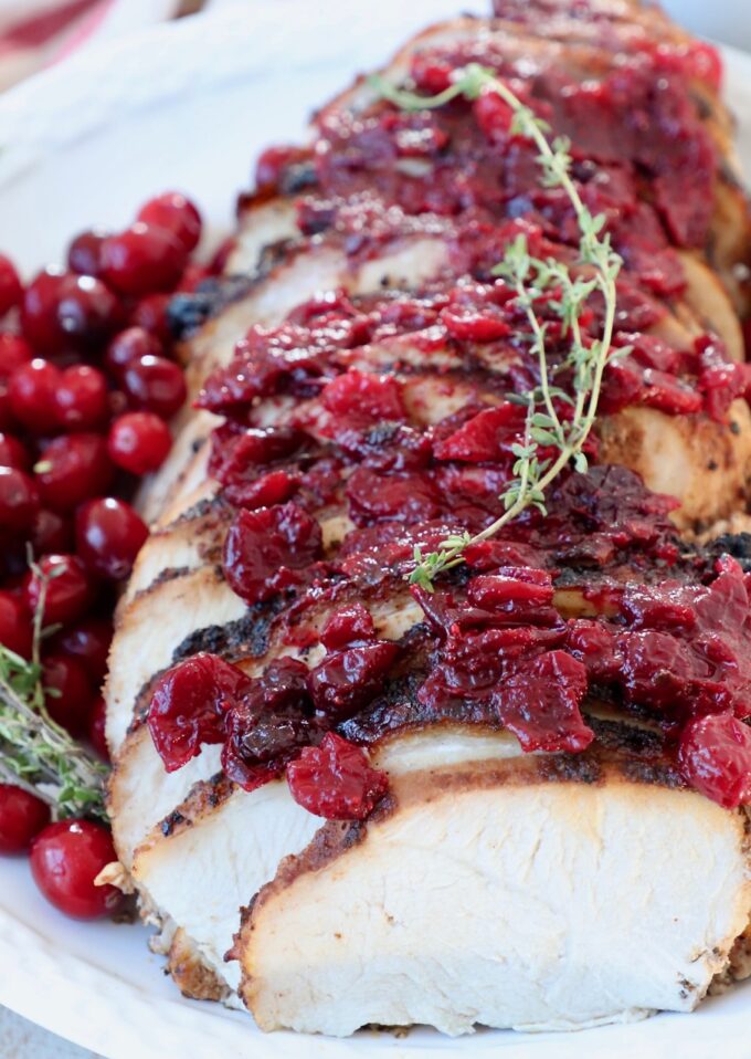 sliced turkey breast on plate covered with cranberry sauce