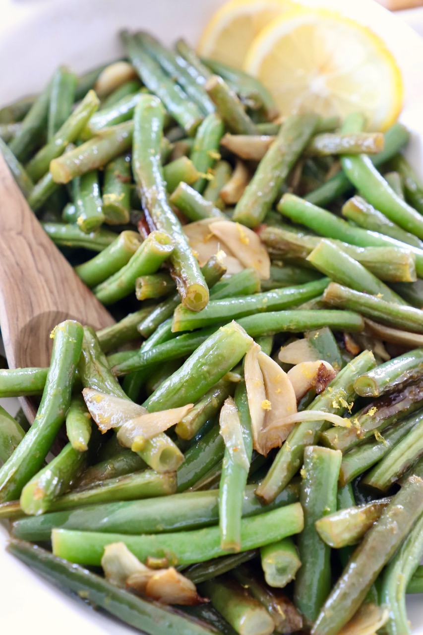 cooked green beans in serving bowl with lemon slices