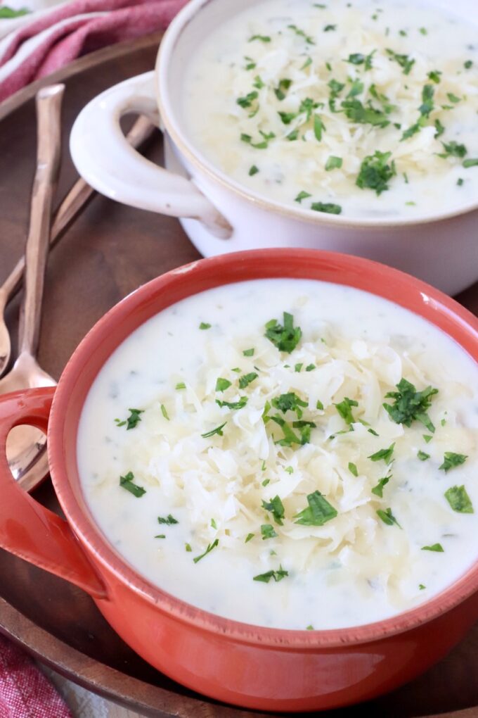 potato soup in bowls topped with shredded cheese and chopped parsley
