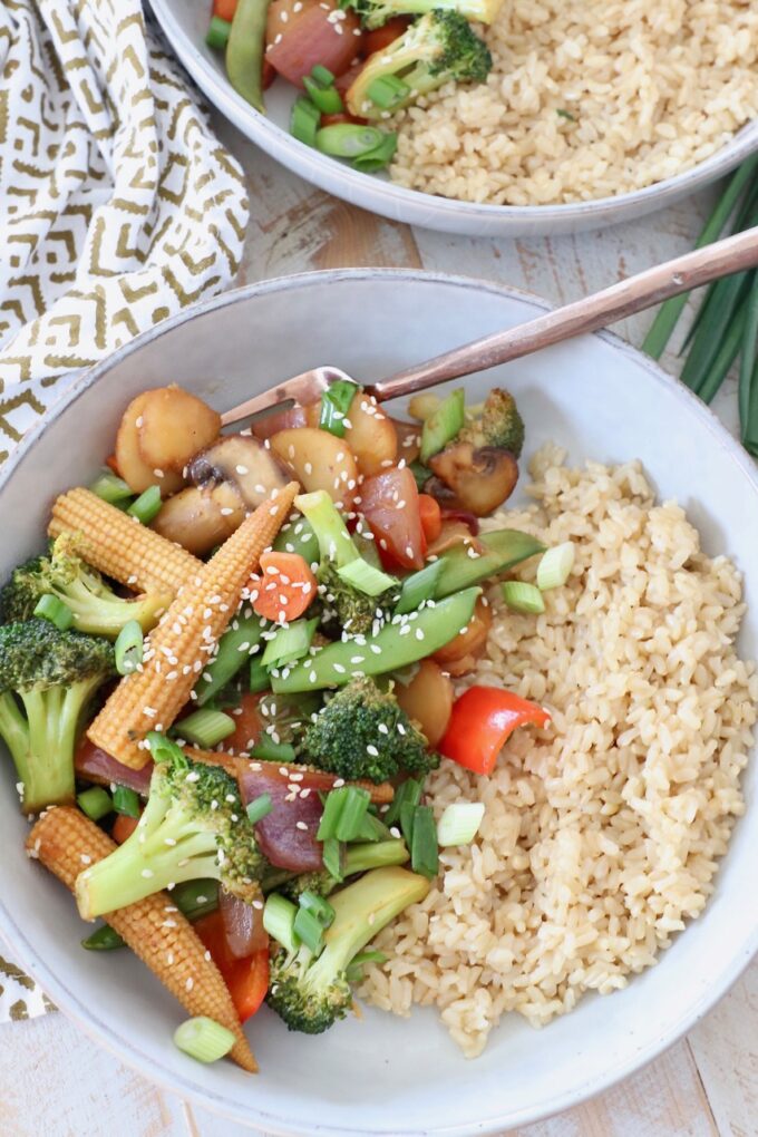 stir fry vegetables in bowl with brown rice and fork