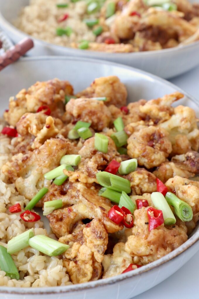 fried cauliflower tossed with general tso's sauce in bowl with brown rice