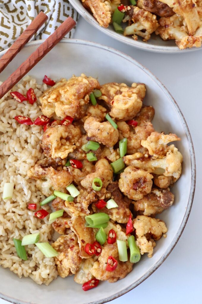 fried cauliflower tossed in general tso sauce in bowl with brown rice