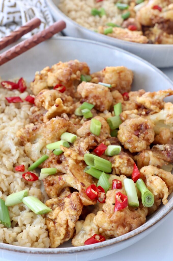 fried general tso cauliflower in bowl with diced red chilies and green onions
