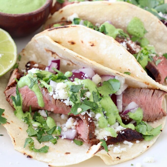steak tacos on plate with lime and cilantro