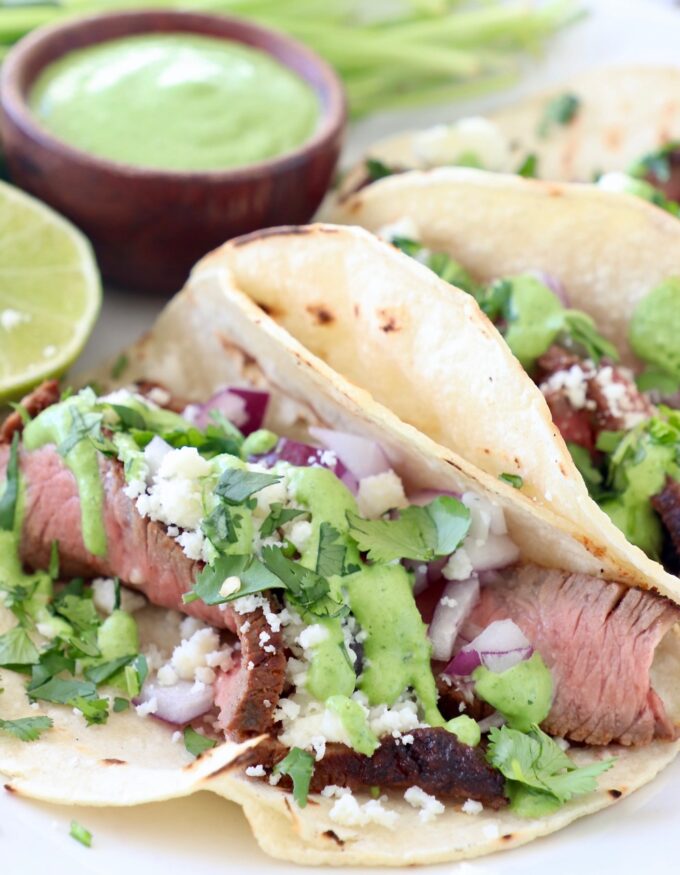 steak tacos on plate with creamy cilantro sauce