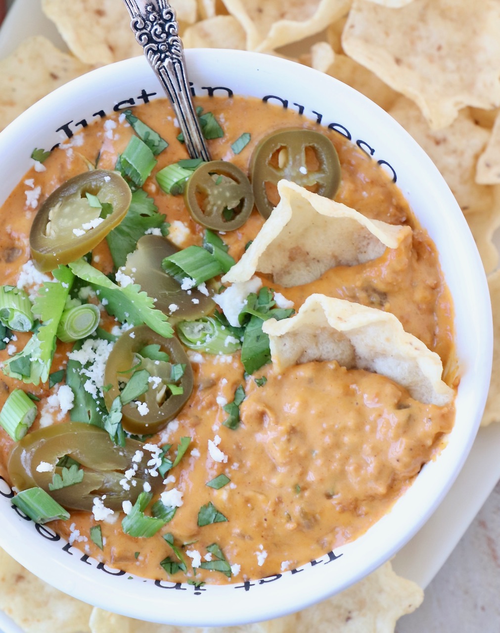 chorizo queso dip in bowl with tortilla chips and sliced jalapenos