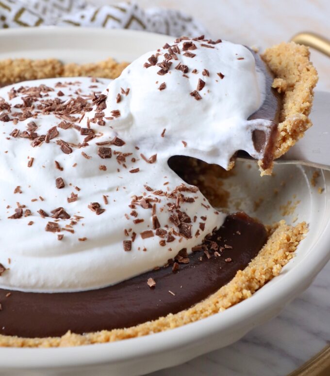 slice of pie lifted out of chocolate pie with whipped cream topping