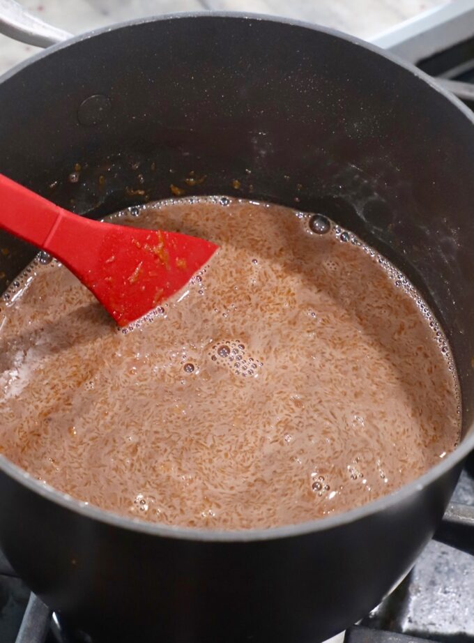red spoon stirring chocolate filling in saucepan