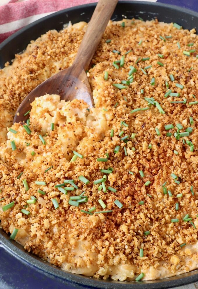 serving spoon in skillet of smoked mac and cheese topped with chopped chives