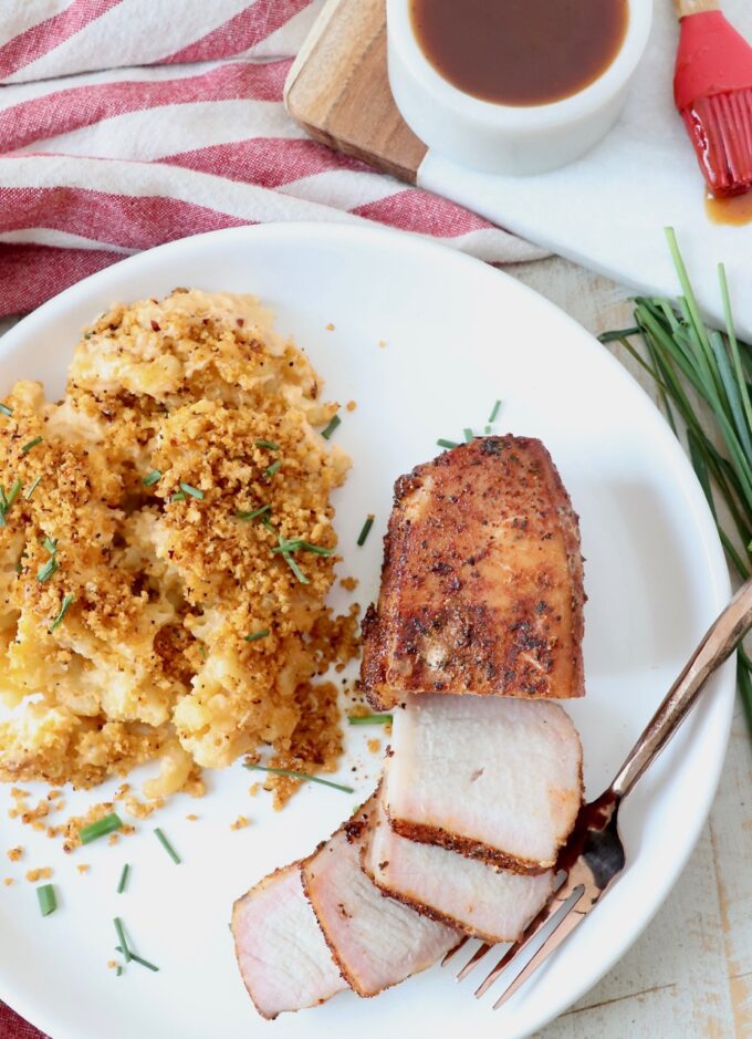 sliced smoked pork chop on plate with mac and cheese