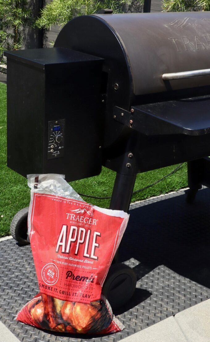 bag of apple pellets sitting next to a smoker outside