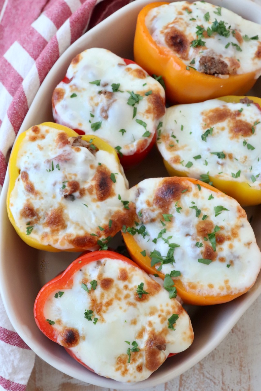 stuffed bell peppers topped with melted mozzarella cheese in baking dish